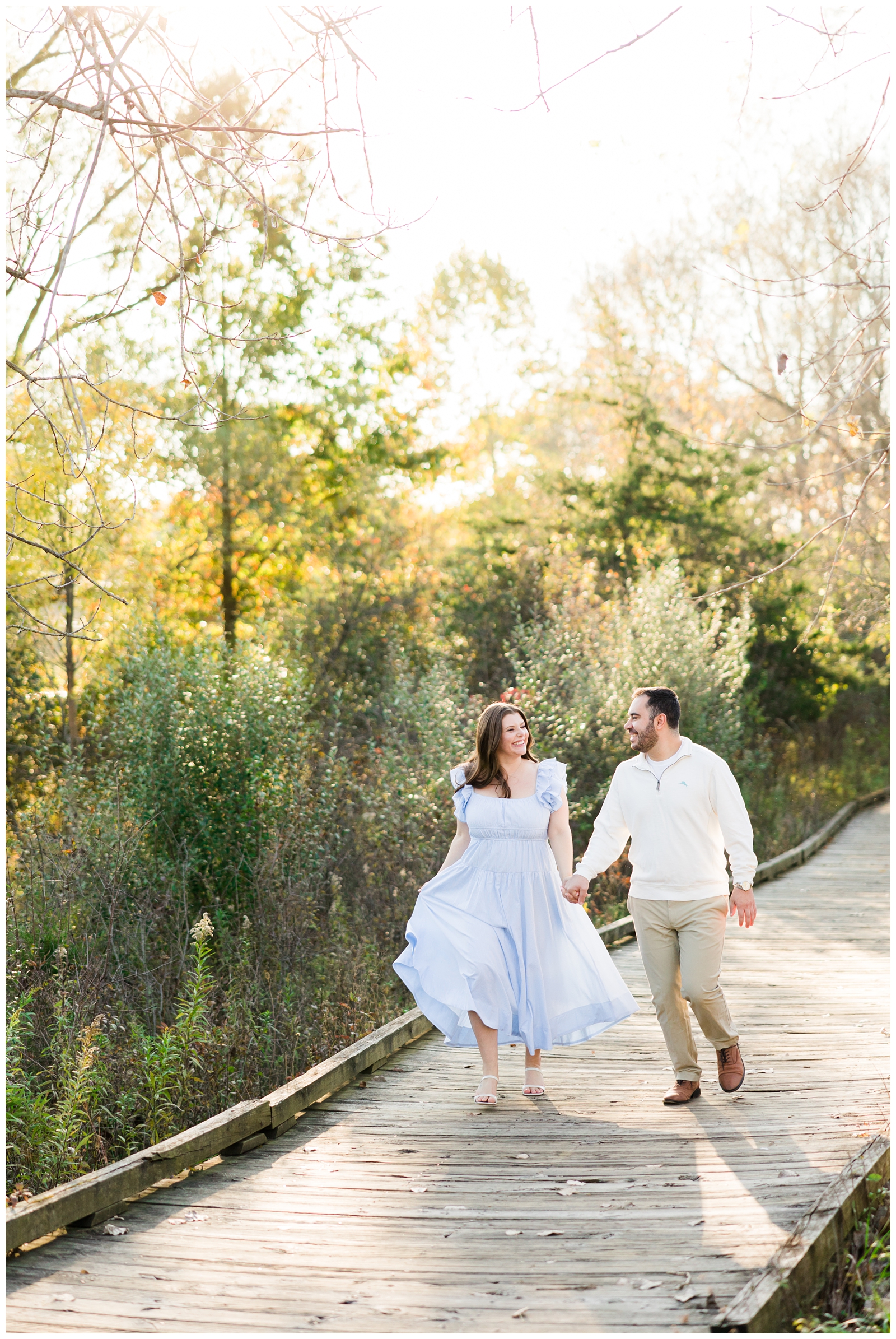 couple holding hands walking across bridge at engagement session